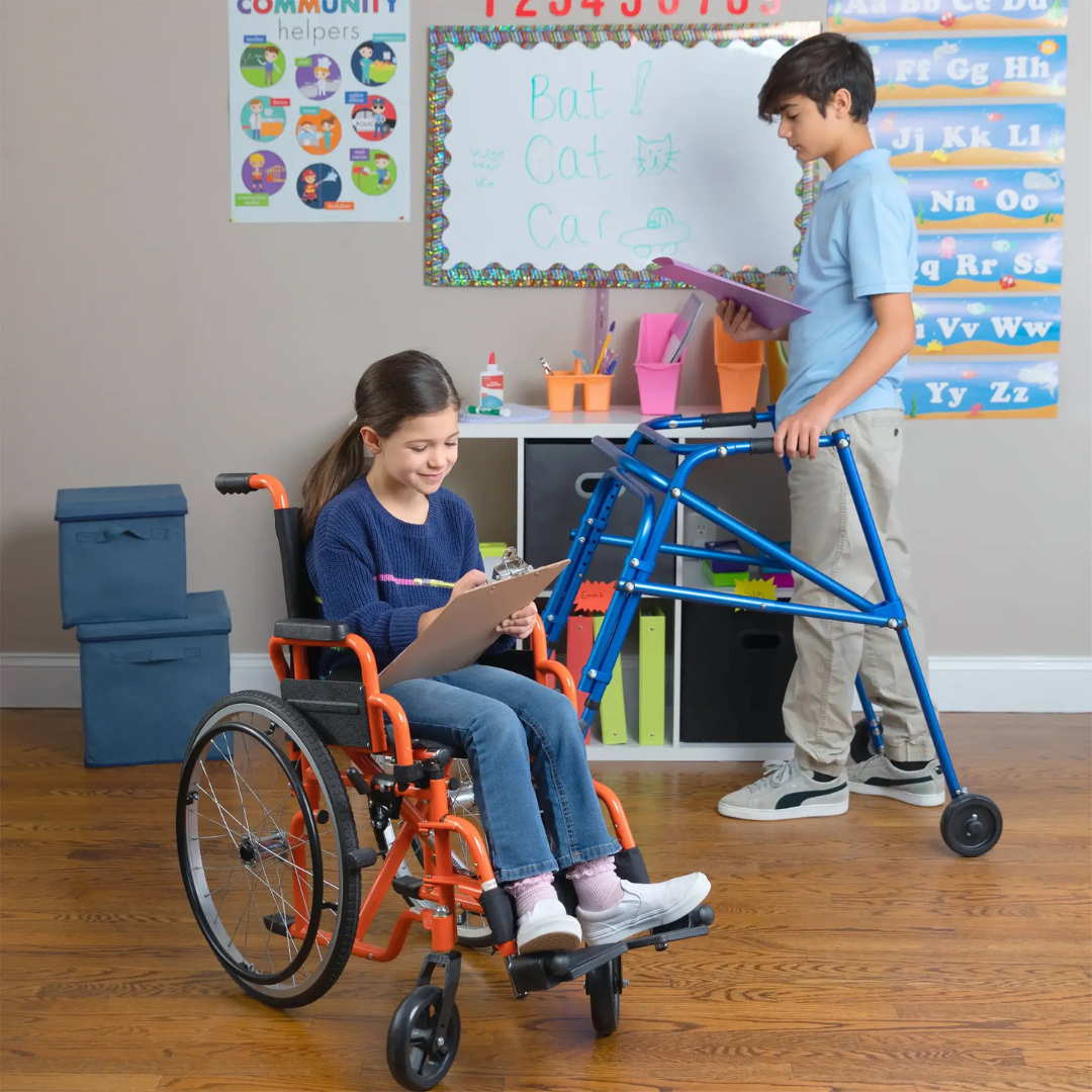 A girl in a Circle Specialty ZIGGO Pediatric Wheelchair and a boy using a walker write on clipboards in a colorful classroom filled with educational posters and storage bins.