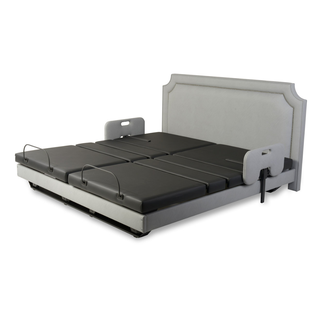 The Assured Comfort® Signature Series Hi-Low Adjustable Bed features a padded headboard, segmented black mattress, side safety rails, foldable sections, and metal handles for improved support and accessibility.
