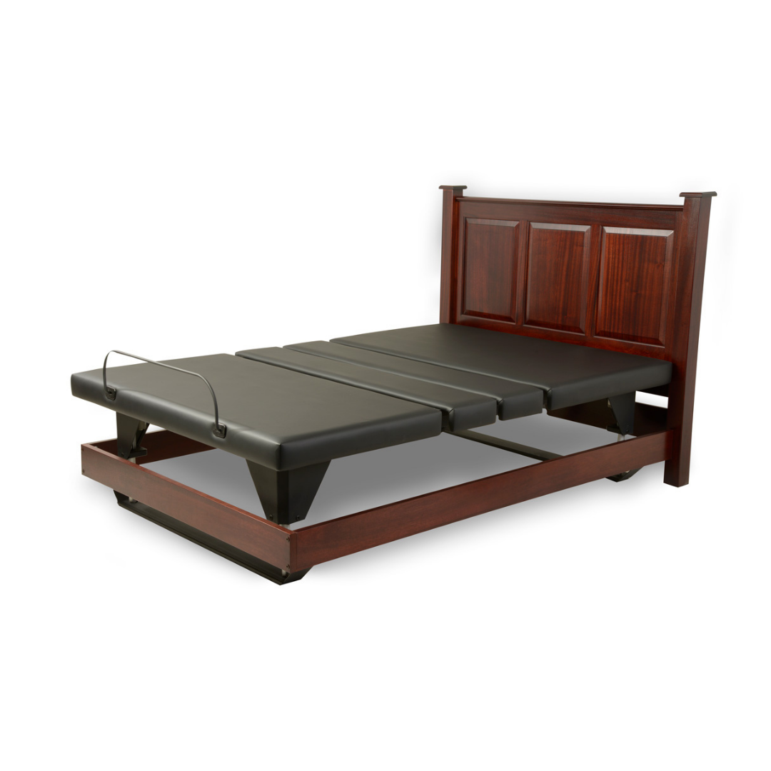 The Assured Comfort® Signature Series Hi-Low Adjustable Bed features a wooden frame, dark wood headboard, and dual black mattress sections, shown partially elevated for ergonomic positioning.