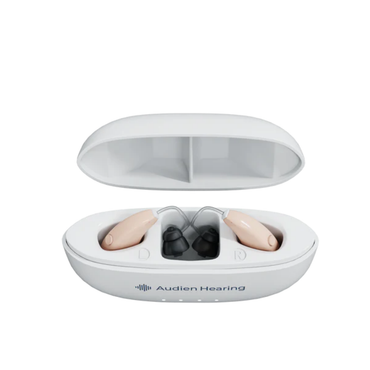 A white oval case labeled Audien Hearing is open, showing two beige Audien Hearing ION Pro Over-The-Ear High Def Hearing Aids with A2™ MAX Chip technology in left and right charging slots.