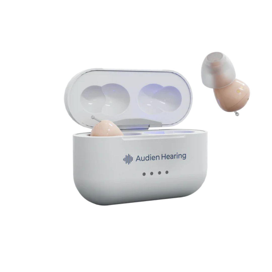 The Audien Hearing Atom Pro 2 In-Ear OTC Hearing Aids, shown in beige with one in a white charging case and the other beside it, are displayed against a white background.