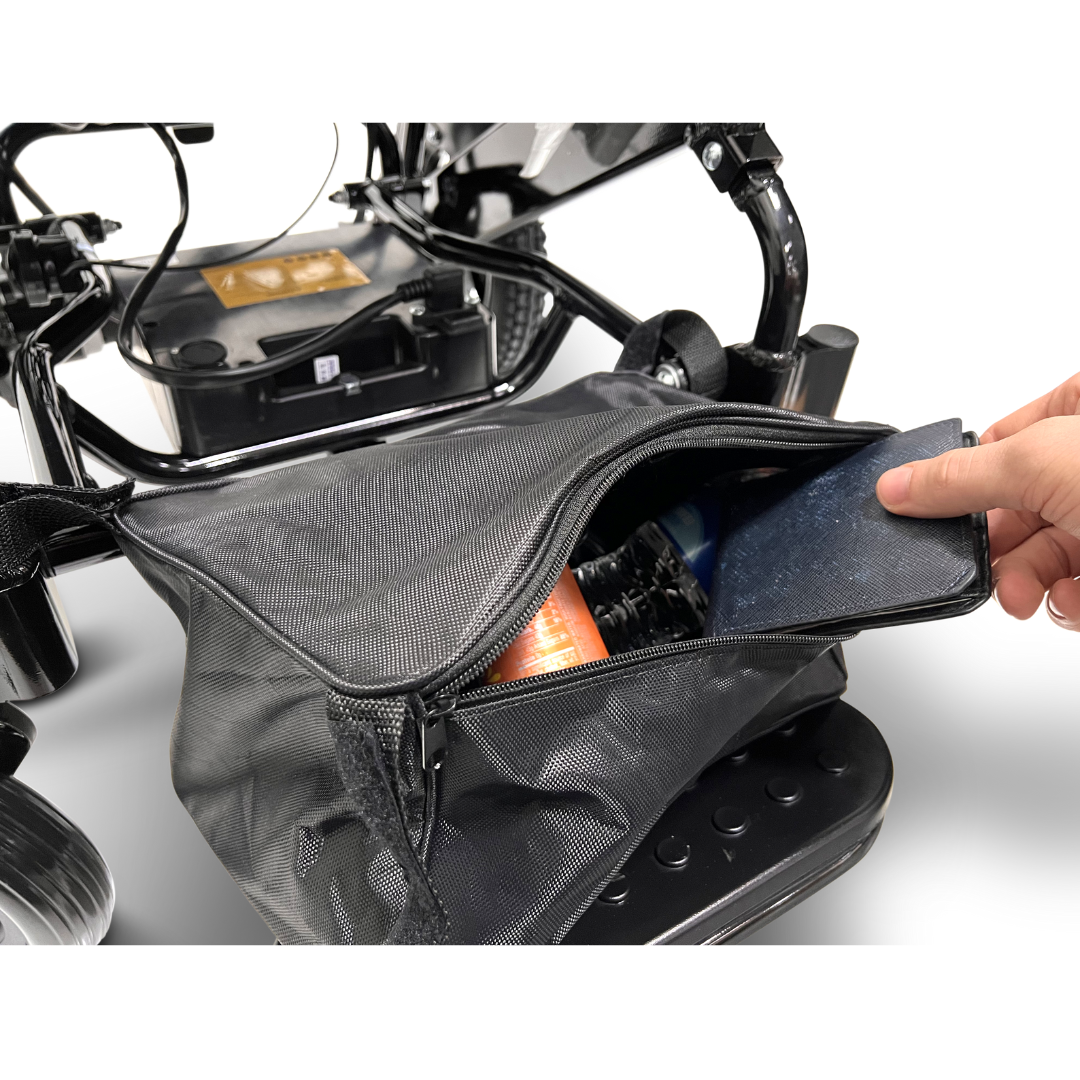 A person opens a black mesh bag attached to the ComfyGo MAJESTIC IQ-8000 Remote Controlled Lightweight Electric Wheelchair, revealing various colorful spray cans inside. The focus is on the lightweight bag's compartment and its contents.