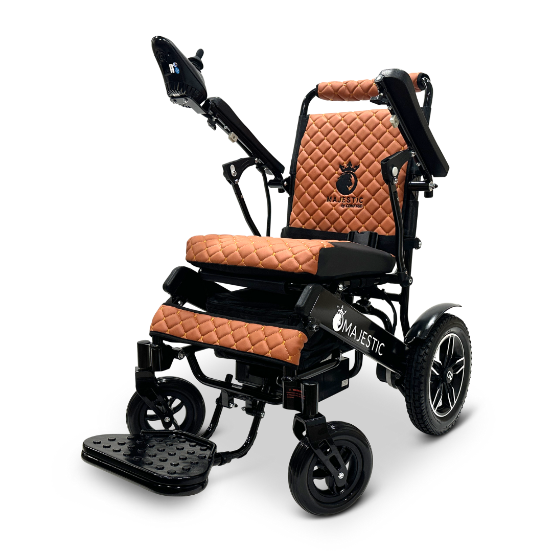 Introducing the ComfyGo MAJESTIC IQ-8000 Remote Controlled Lightweight Electric Wheelchair, designed with travel-friendliness and luxury in mind. It features quilted brown leather padding, a control panel conveniently located on the armrest, and sleek black wheels. This wheelchair is lightweight yet remarkably durable, with the Majestic brand proudly displayed on the backrest and side for an elegant touch.