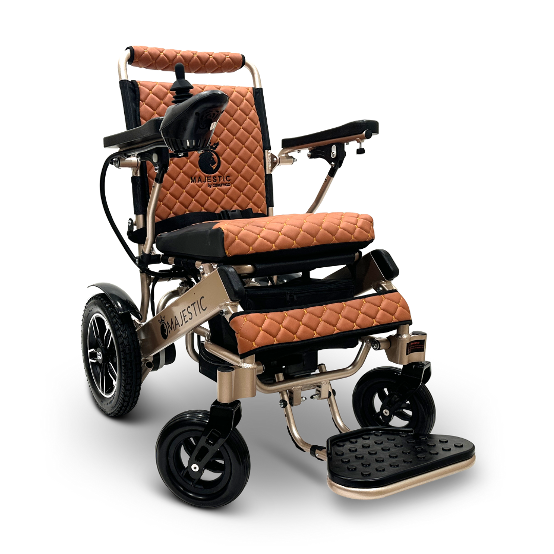 Introducing the ComfyGo MAJESTIC IQ-8000, a lightweight and luxurious electric wheelchair in tan and black. It boasts quilted upholstery and proudly displays the Majestic branding on its backrest. This travel-friendly model comes complete with sturdy wheels, a footrest, and an intuitive joystick control conveniently located on the armrest.