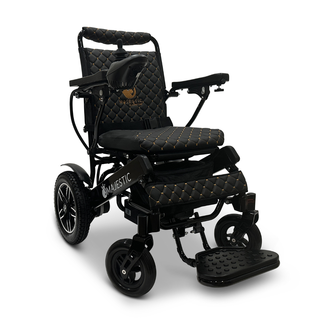 The ComfyGo MAJESTIC IQ-8000 is a travel-friendly and lightweight electric wheelchair in black and gold, featuring a quilted design on the seat and backrest. It includes a joystick on the right armrest for easy control, four sturdy wheels for mobility, and is labeled with Majestic on the side.