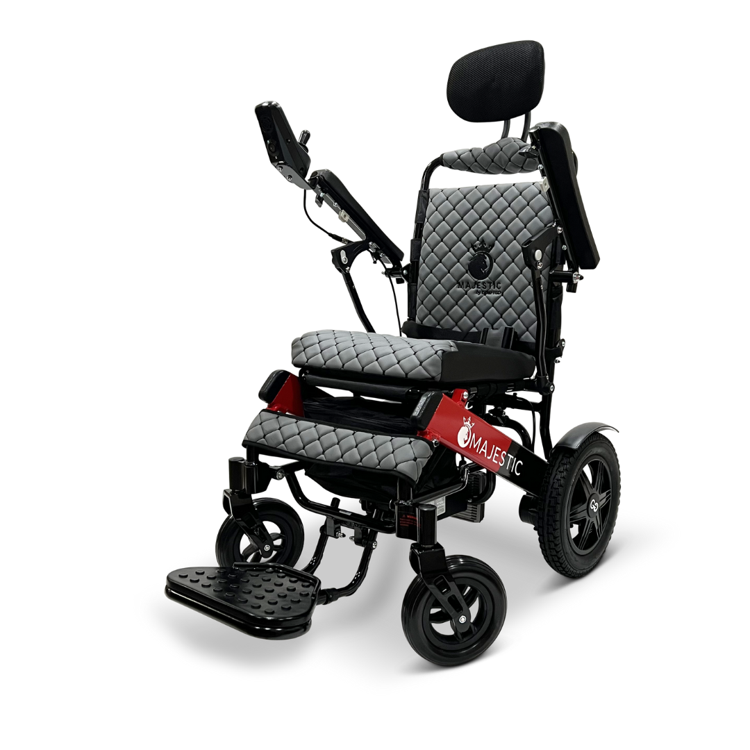 The ComfyGo MAJESTIC IQ-9000 Auto Recline Remote Controlled Electric Wheelchair showcases a luxurious quilted gray and black seat with armrests, all set against its distinctive red Majestic-labeled frame. Powered by brushless silent motors and controlled via a digital joystick, this wheelchair offers unmatched comfort and mobility, featuring four wheels along with a footrest and headrest.