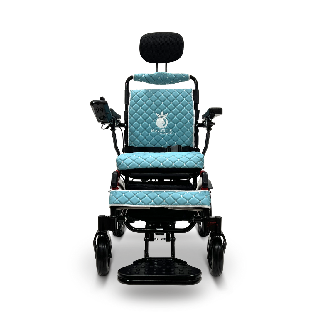 The ComfyGo MAJESTIC IQ-9000 Auto Recline Remote Controlled Electric Wheelchair, elegantly presented against a white background, comes in a sleek black and blue design. It offers a quilted seat with a headrest and features a digital joystick controller on the armrest. The wheelchair also showcases the Majestic branding on the backrest and is powered by brushless silent motors.