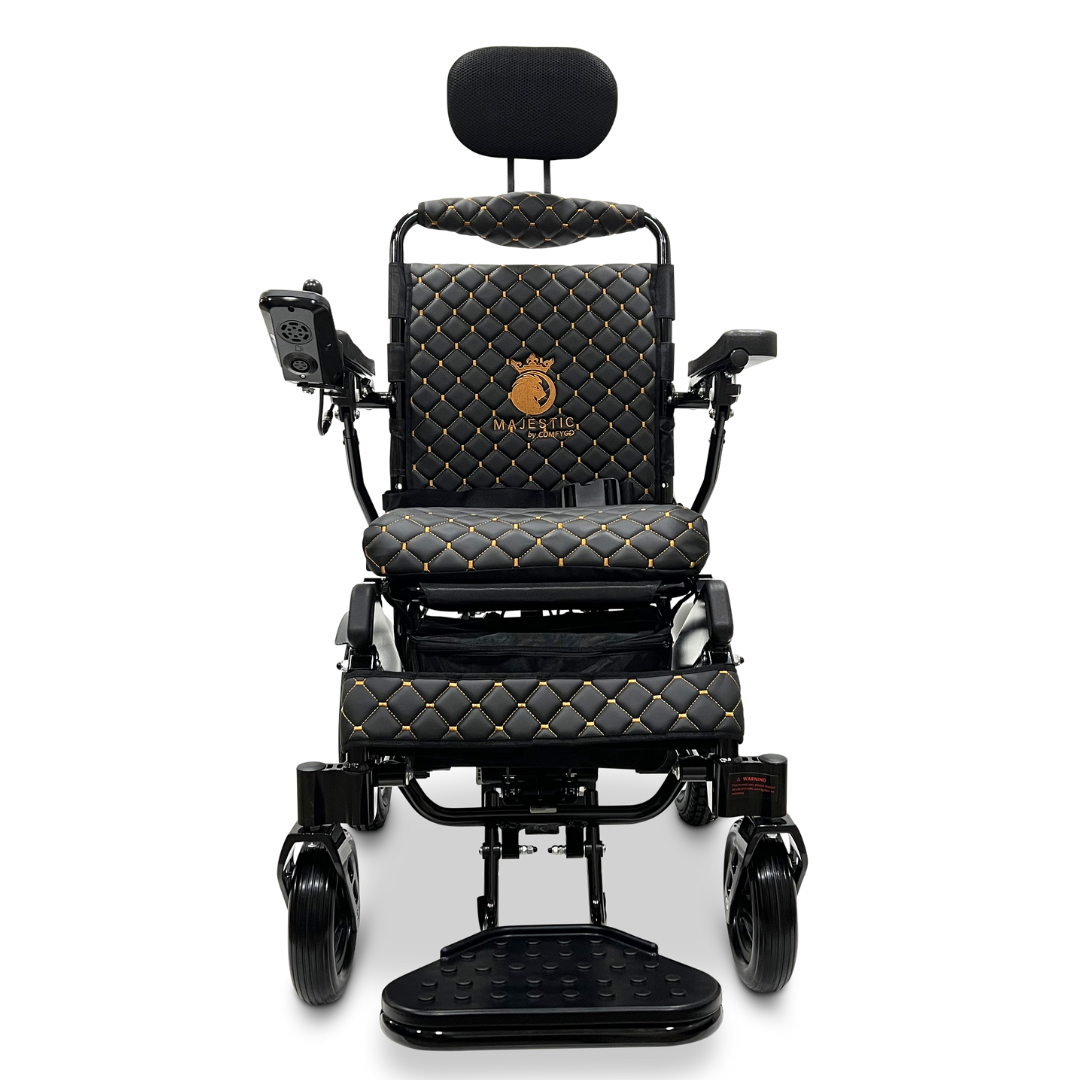 The ComfyGo MAJESTIC IQ-9000 Auto Recline Remote Controlled Electric Wheelchair showcases a sleek black electric design with luxurious quilted upholstery and elegant gold accents. It includes a digital joystick controller on the right armrest, a raised footrest that reveals small front wheels, and is powered by brushless silent motors for smooth and serene mobility.