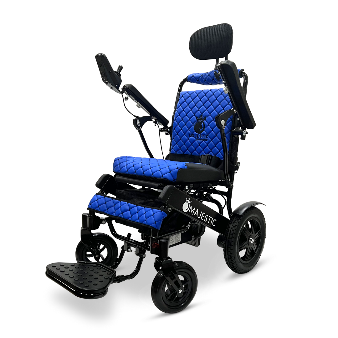 The ComfyGo MAJESTIC IQ-9000 Auto Recline Remote Controlled Electric Wheelchair features a sleek black frame, blue quilted cushioning, and advanced technology such as brushless silent motors. It is equipped with large rear wheels, an adjustable footplate, and a digital joystick controller located on the armrest to ensure smooth navigation. The brand name "Majestic" is prominently displayed on the frame.