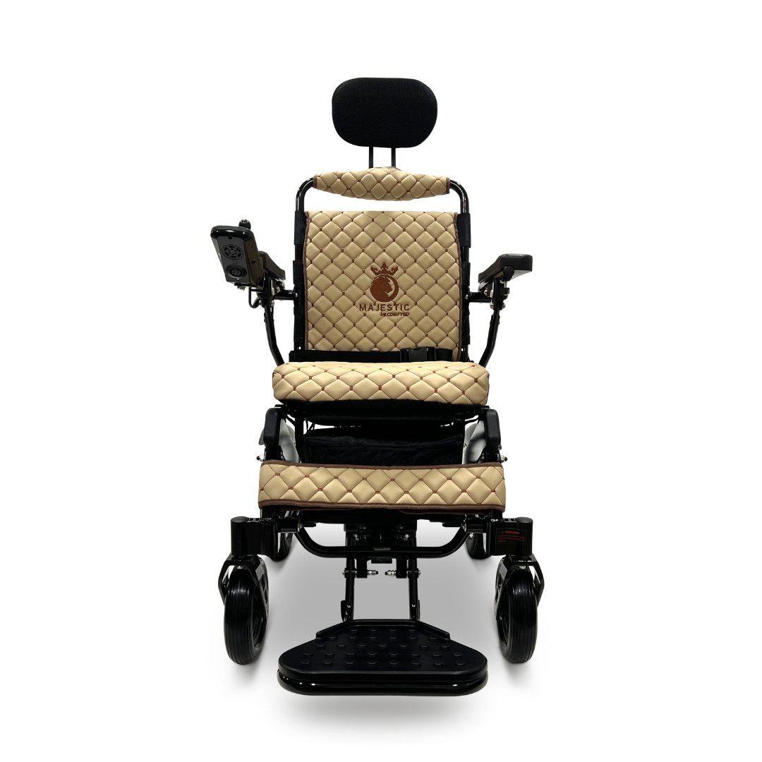 The ComfyGo MAJESTIC IQ-9000 Auto Recline Remote Controlled Electric Wheelchair is a beige, quilted electric model with black accents and comes with a headrest. It features brushless silent motors and a digital joystick controller positioned on the right armrest. The design boasts two large front wheels, a footrest, and a backrest adorned with a small printed logo.