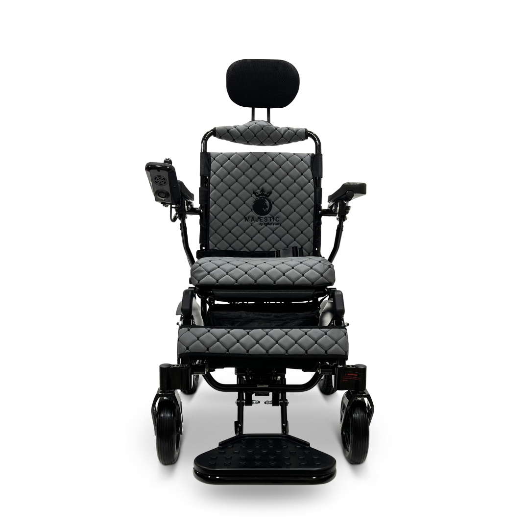The ComfyGo MAJESTIC IQ-9000 Auto Recline Remote Controlled Electric Wheelchair showcases a sophisticated black and grey design, complete with quilted padding on the seat, backrest, and armrests. It includes a digital joystick controller situated on the right armrest, along with a headrest and footrests, all powered by brushless silent motors for an effortlessly smooth ride.