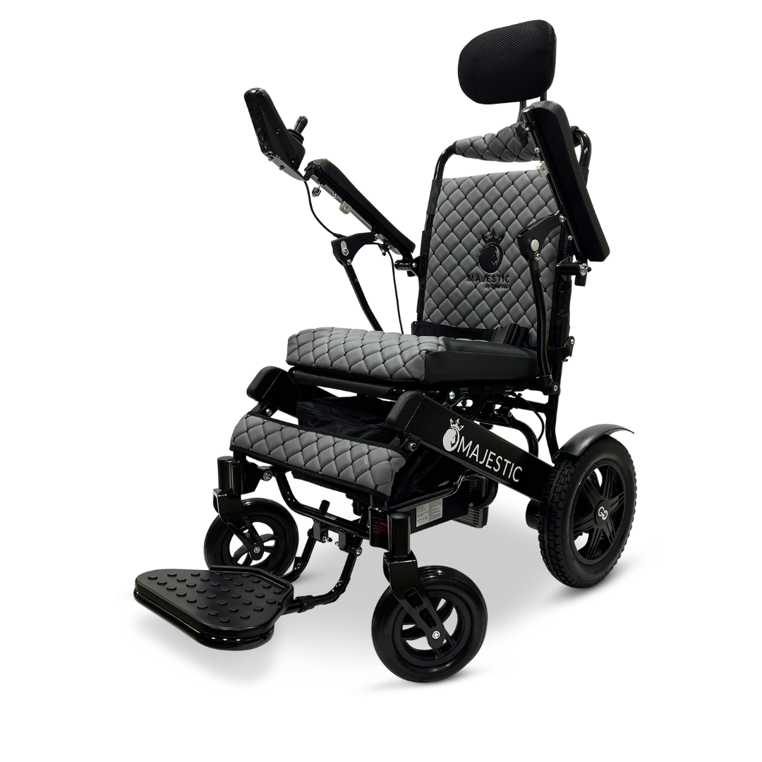 The ComfyGo MAJESTIC IQ-9000 Auto Recline Remote Controlled Electric Wheelchair, featuring a refined quilted design in sleek black, offers a padded headrest and adjustable armrests for added comfort. Its brushless silent motors combined with a digital joystick controller provide seamless operation. With large rear wheels and smaller front ones for improved maneuverability, the Majestic branding is prominently displayed on the side.