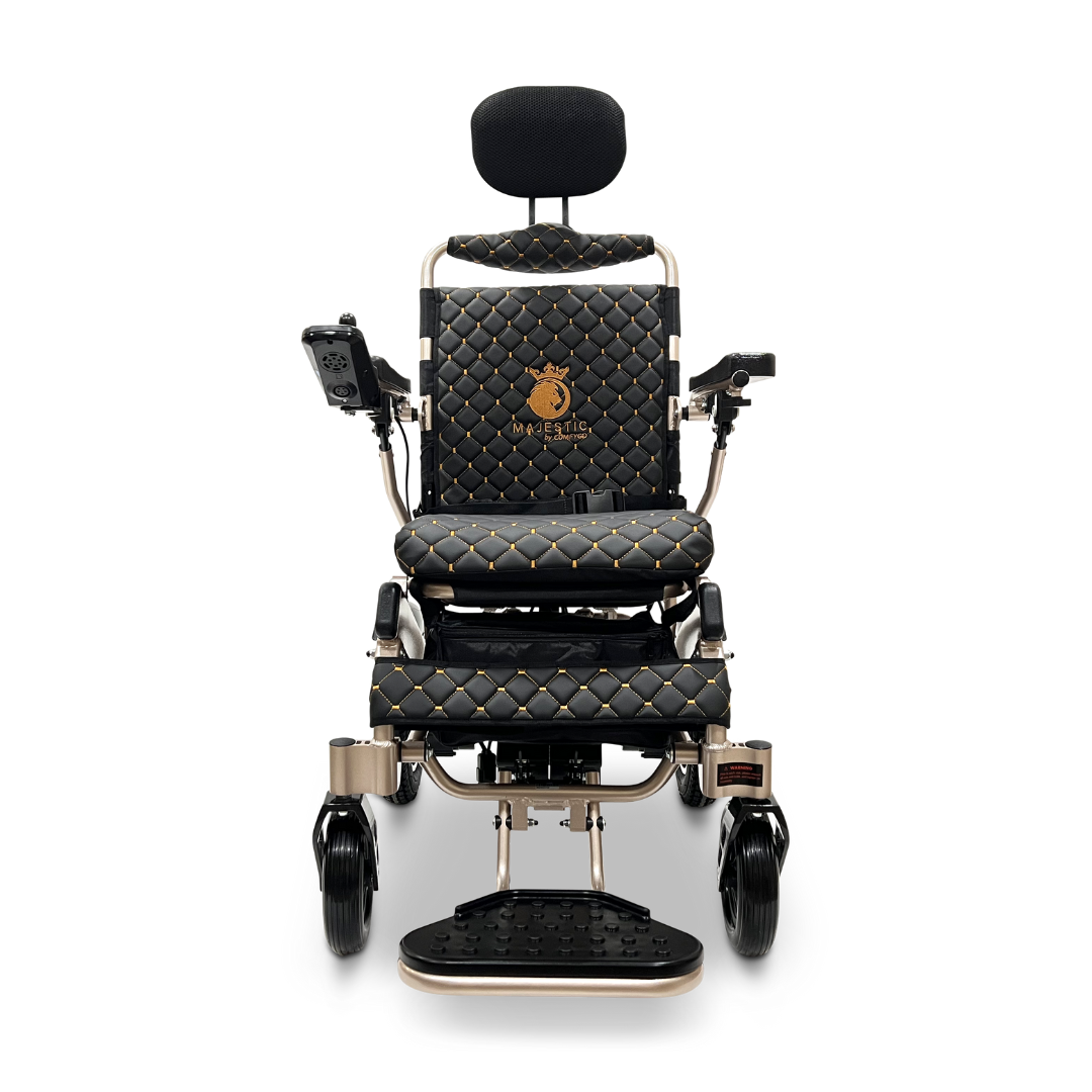 Front view of the elegant ComfyGo MAJESTIC IQ-9000 Auto Recline Remote Controlled Electric Wheelchair in black and gold, showcasing a quilted pattern with a headrest. It includes whisper-quiet brushless motors, a digital joystick controller on the armrest, and a footrest at the base for exceptional comfort and control.