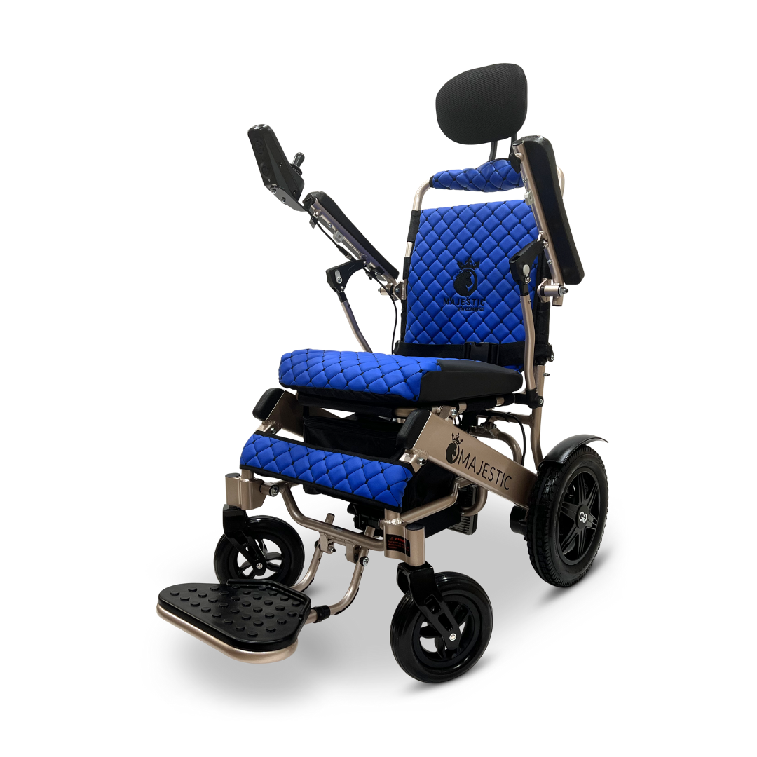 The ComfyGo MAJESTIC IQ-9000 Auto Recline Remote Controlled Electric Wheelchair comes in blue and black, featuring a quilted seat design with an adjustable headrest and footrest. It operates with brushless silent motors and includes two large rear wheels, two smaller front wheels, a metallic Majestic frame, and a digital joystick controller attached to the armrest.