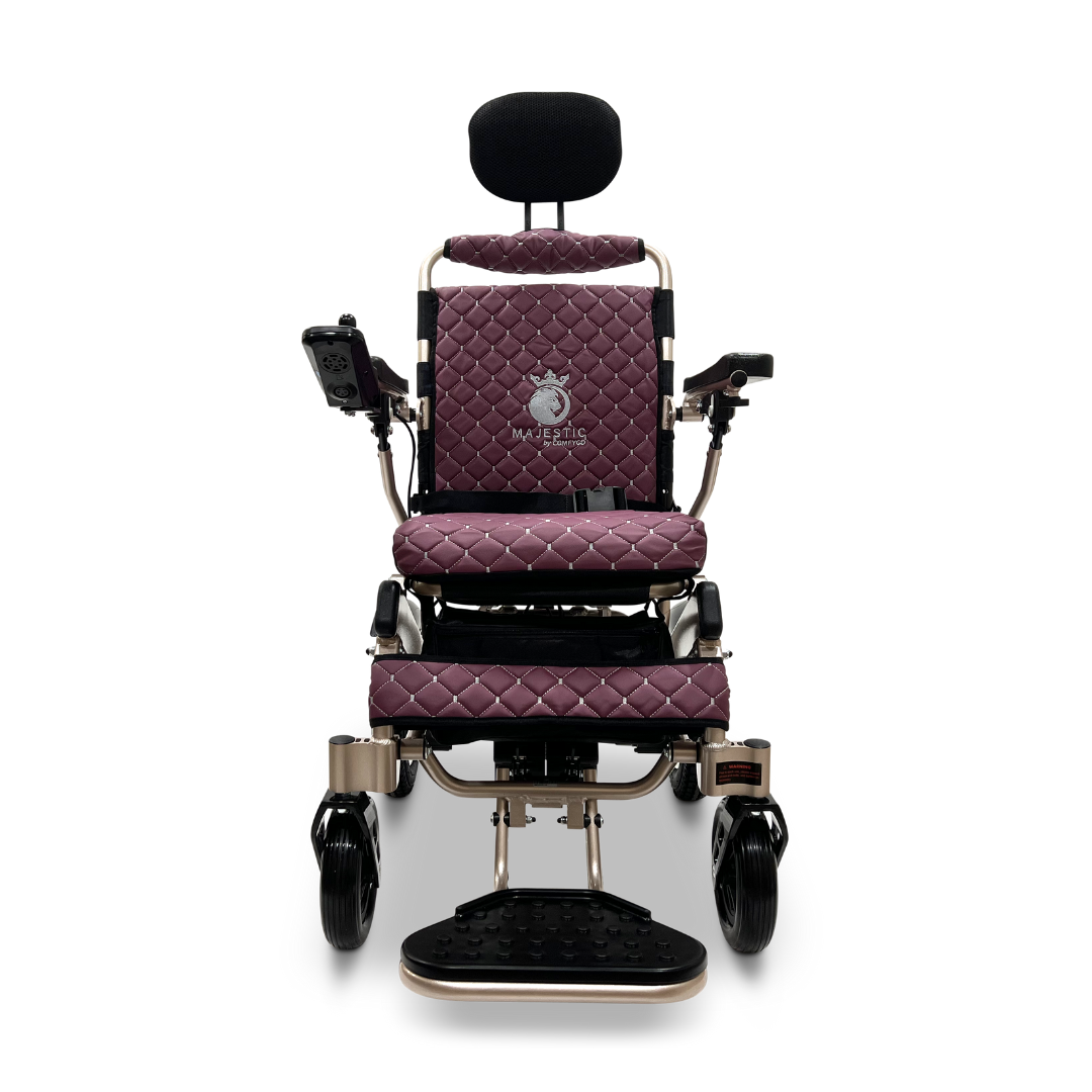The ComfyGo MAJESTIC IQ-9000 Auto Recline Remote Controlled Electric Wheelchair is a sophisticated and modern electric model featuring a maroon quilted seat and backrest. It comes equipped with a headrest, armrests, and a digital joystick controller on the right arm. Its brushless silent motors with black wheels are designed to provide effortless mobility.