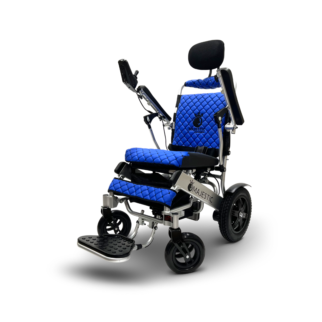 The ComfyGo MAJESTIC IQ-9000 is a blue and black electric wheelchair with a padded seat, backrest, arm supports, footrest, and four wheels. It features auto recline and a precise digital joystick controller. The metallic frame displays Majestic on the side. The chair is set against a white background.