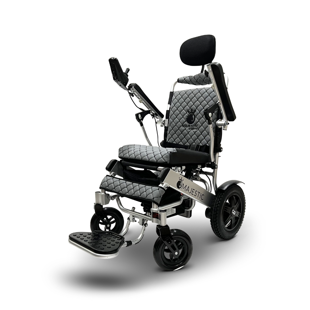 The ComfyGo MAJESTIC IQ-9000 electric wheelchair combines black and silver hues with a quilted seat, backrest, headrest, armrests, footrest, and right-mounted digital joystick controller. Its Majestic branding adorns the front and features automatic reclining for enhanced comfort.