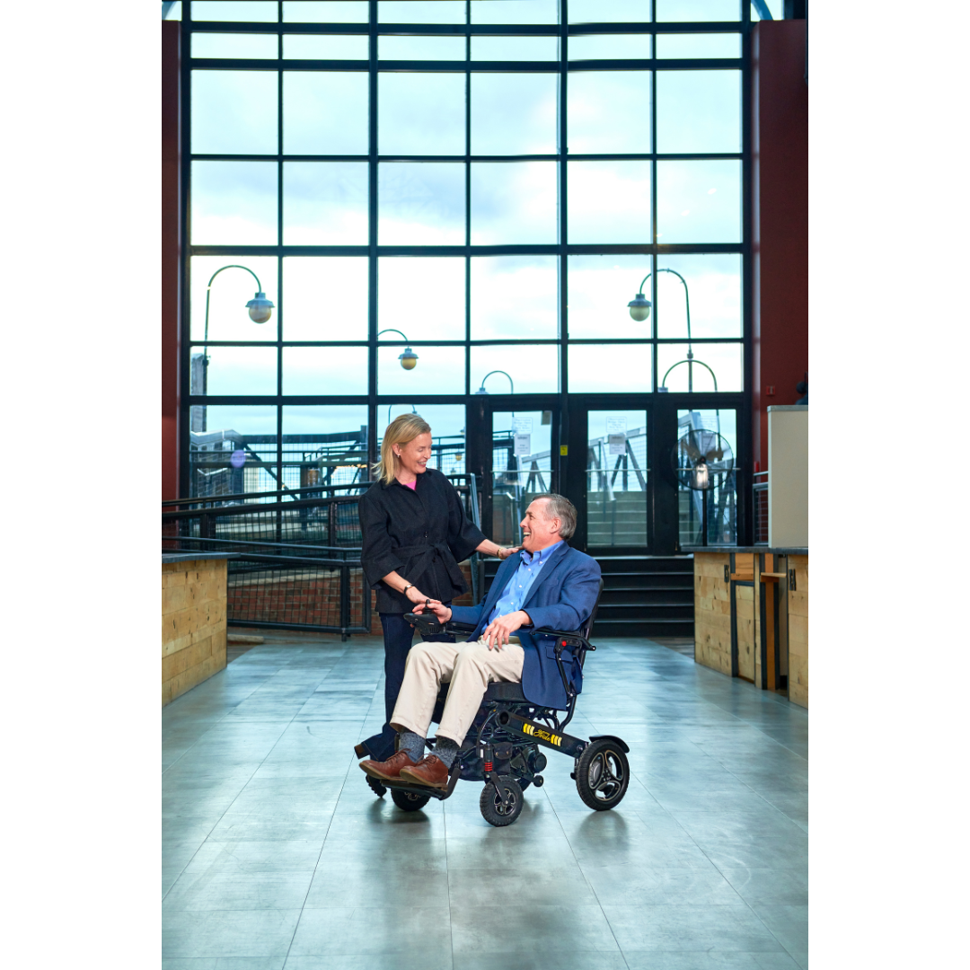 Man and woman at the airport using the Golden Tech Stride Folding Lightweight Powerchair