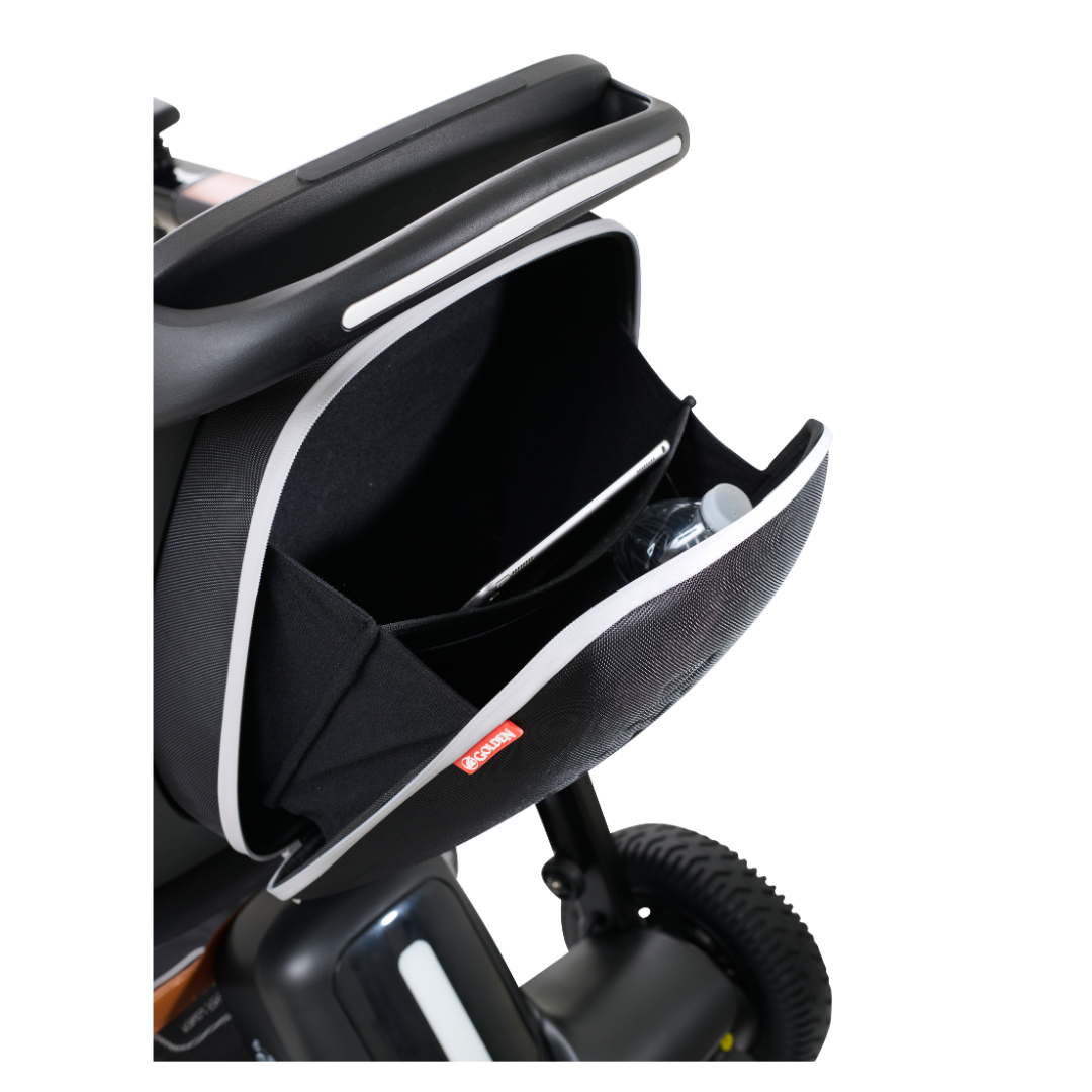 A close-up shows the open storage compartment of a Golden Tech Ally Folding Power Wheelchair revealing a tablet running the Smart Control Mobile App and a water bottle. The black compartment with white trim is handlebar-mounted, making it an ideal travel companion.