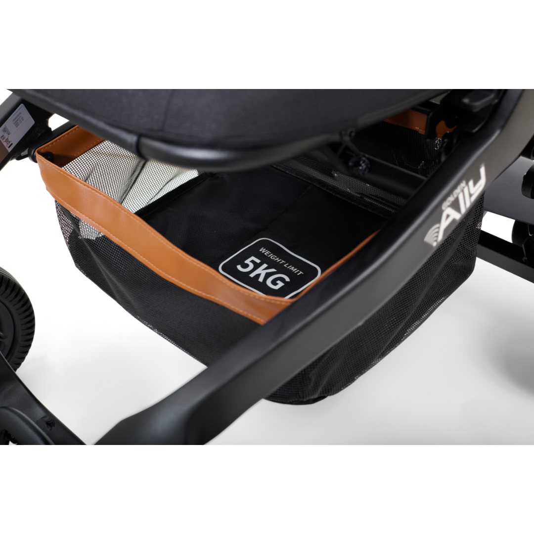 Close-up of a black Golden Tech Ally Folding Power Wheelchairs storage basket labeled Weight Limit 5KG. Perfect for travel, it features a brown trim and is under the seat. The frame is black with partially visible wheels.