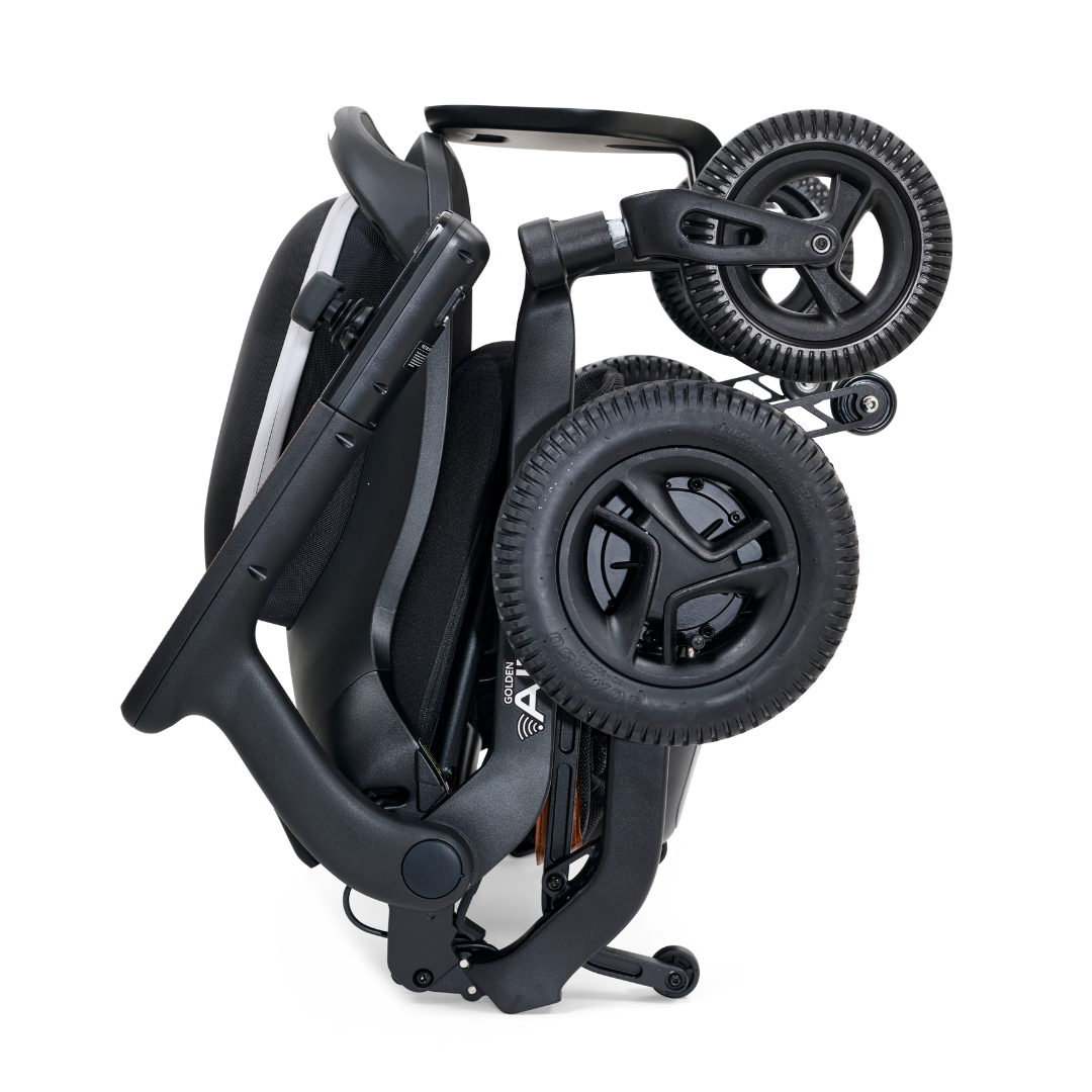 The Golden Tech Ally Folding Power Wheelchair, with its mobile app control, stands upright in black and white when folded. This travel companion features a compact design with a handle for easy carrying and storage.
