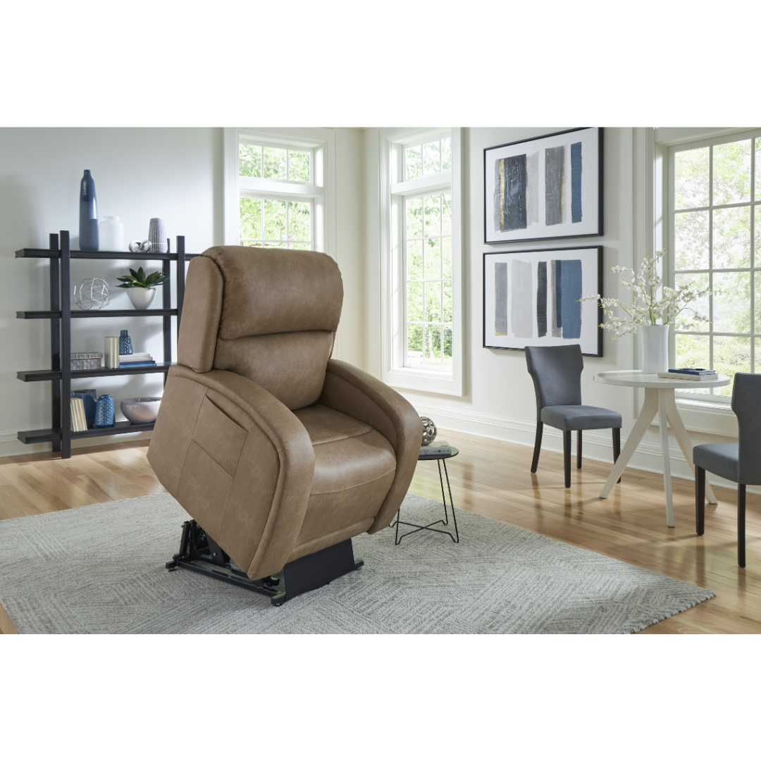 A beige Golden Tech PR761 EZ Sleeper Recliner with Lift Assist & Twilight Recline complements a modern living room featuring large windows, light walls, wooden floors, a gray rug, black shelving unit, round white table with gray chairs, and abstract artwork for ultimate relaxation.