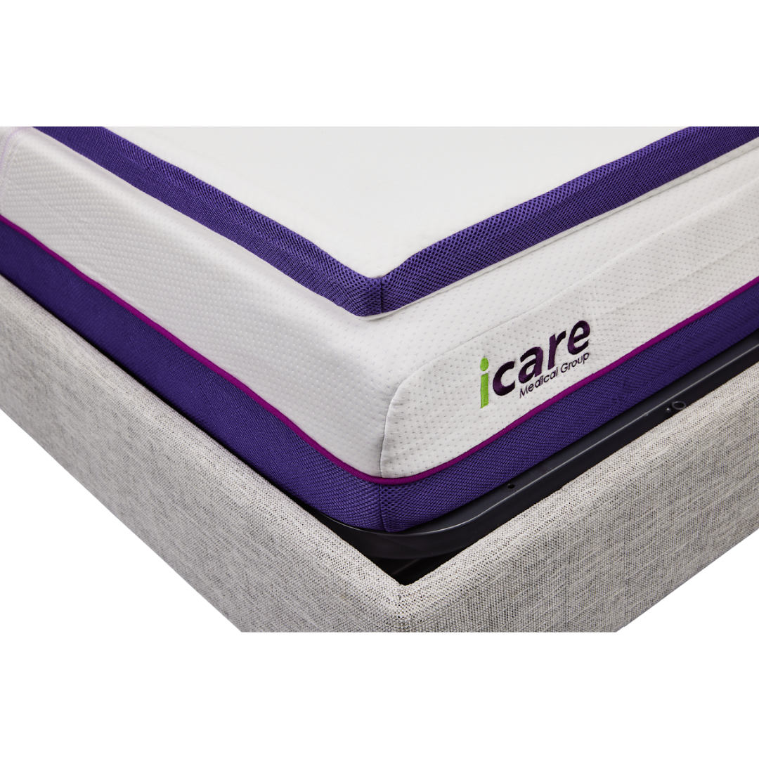 Close-up of the iCare Medical IC100 Static Partner Non-Adjustable Bed, showcasing a mattress with white and purple antibacterial vinyl fabric and the icare Medical Group logo, set atop a light grey hospital-grade upholstered base.