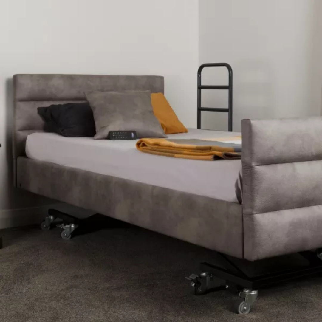 The iCare Medical Bed Safety Rails provide bedside support and fall prevention with high black side rails on a modern adjustable bed featuring a grey upholstered frame, grey and mustard pillows, folded mustard blanket, remote control, and wheels.