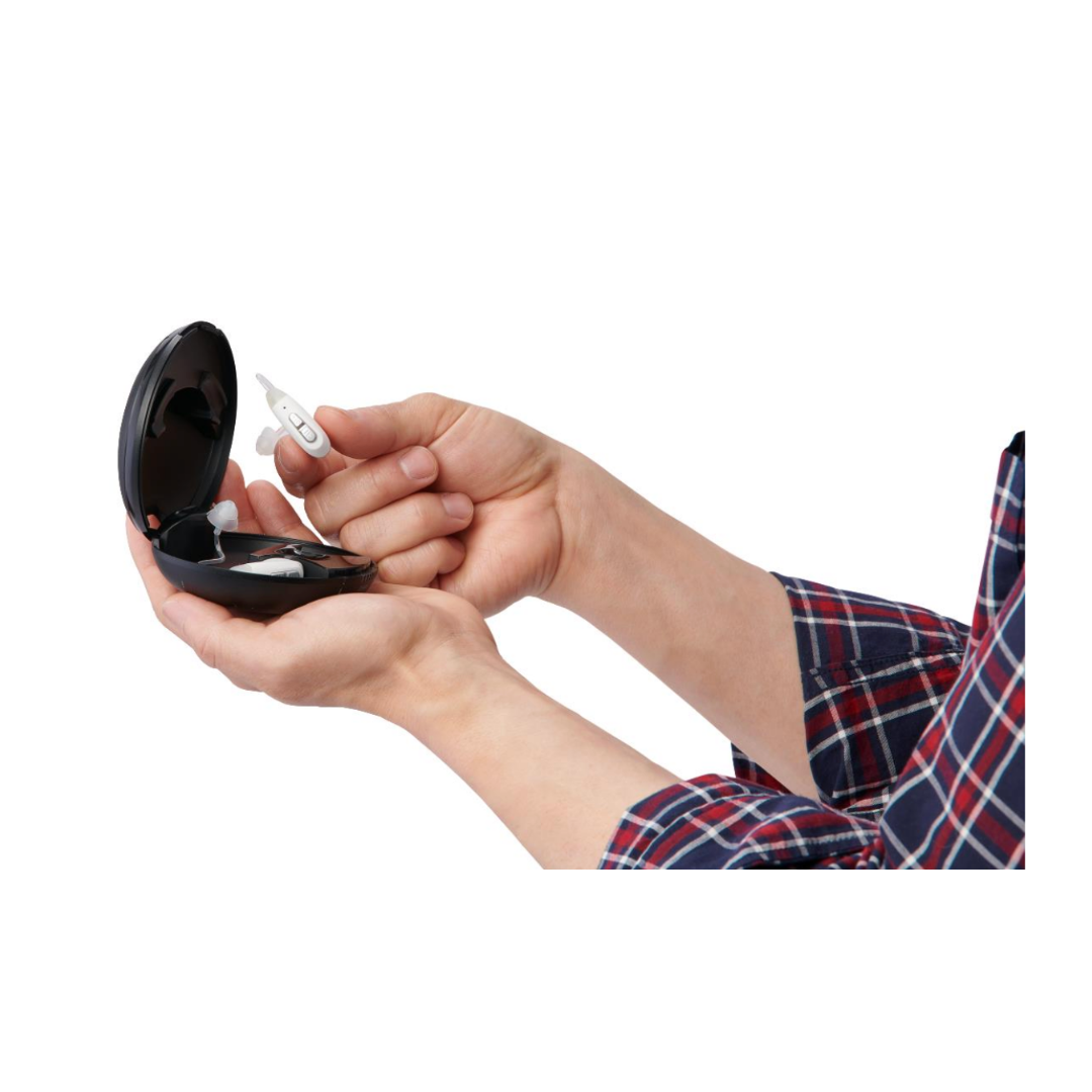 A person in a plaid shirt holds an open black case in one hand and the Medline Rechargeable Digital OTC Hearing Aid (Behind-The-Ear Style) in the other.