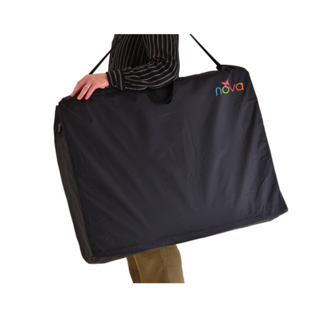 A person carries the Nova Extra-Large Carry & Travel Bag for Rollator Walkers & Transport Chairs, featuring a colorful “nova” logo on the top corner, using a shoulder strap. Only part of their body is visible.