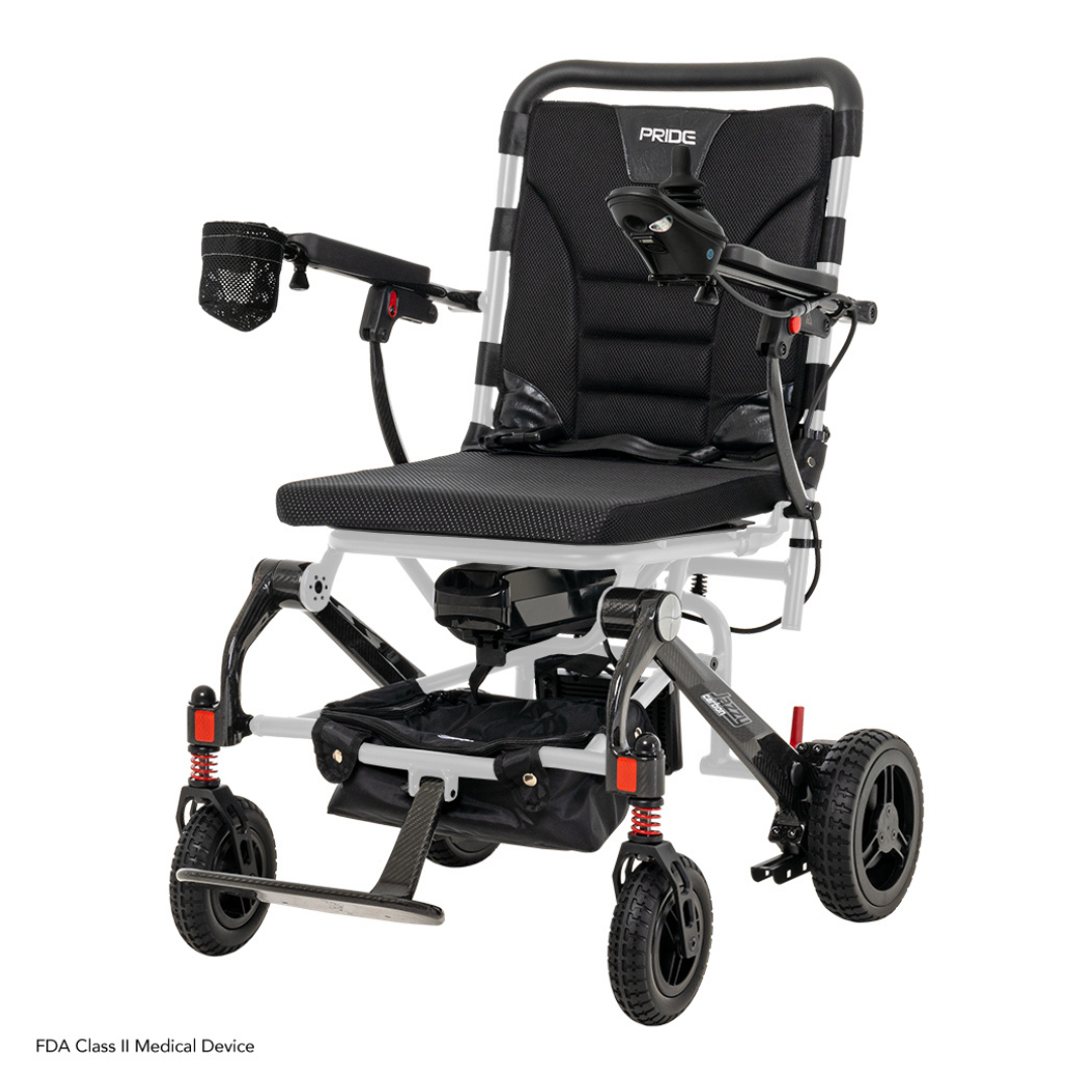 The Pride Mobility Jazzy® Carbon Ultralite Powerchair is a sleek, lightweight travel power chair featuring a black seat, armrests, footrest, small front wheels, larger rear wheels with red shock absorbers, and an airline-compliant lithium battery. It includes a removable joystick with USB charger for added convenience.