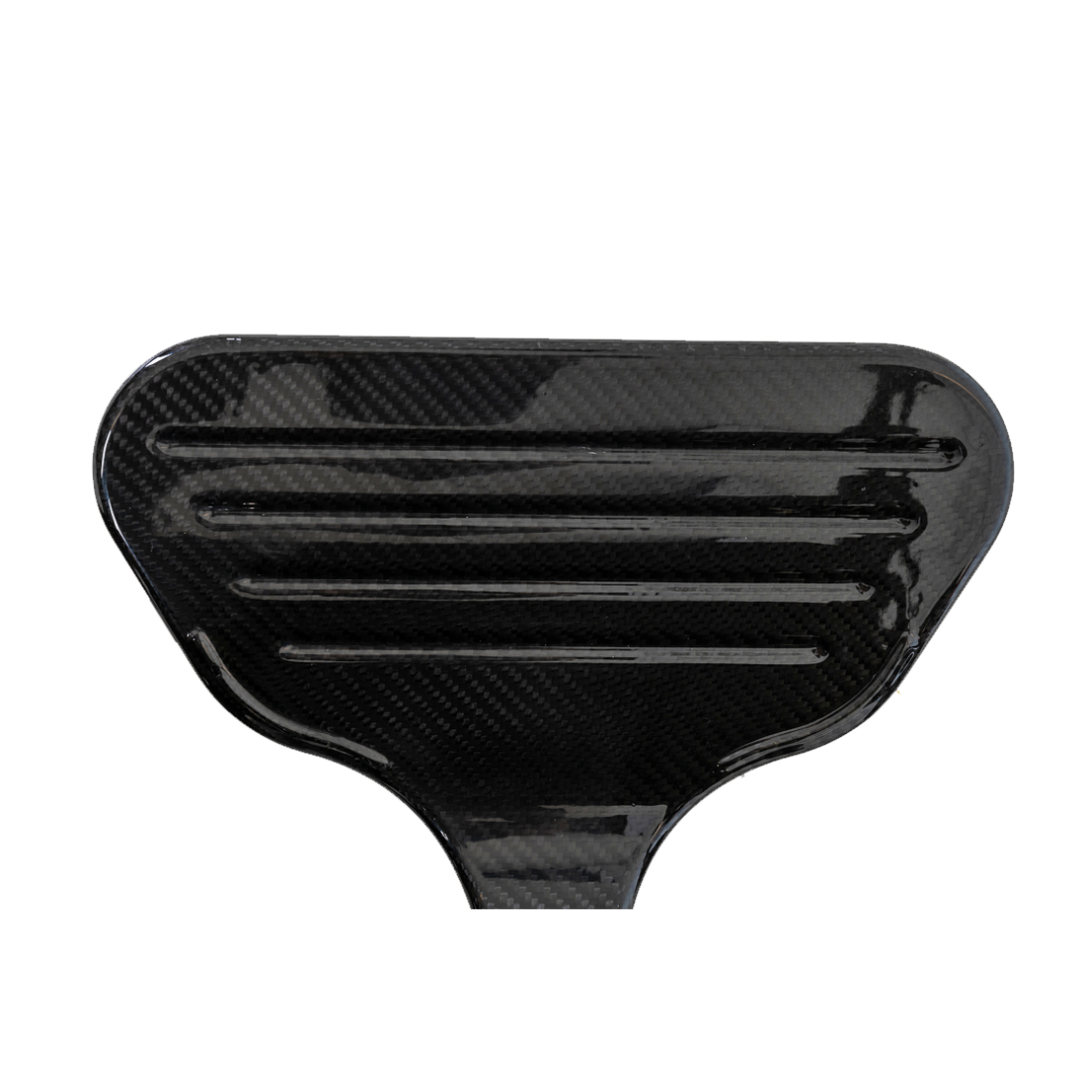 Close-up of a black Pride Mobility Jazzy® Carbon Ultralite Powerchair, highlighting its glossy carbon fiber finish with horizontal grooves. The ultra-lightweight texture is smooth and reflective, resembling a paddle or vehicle component.