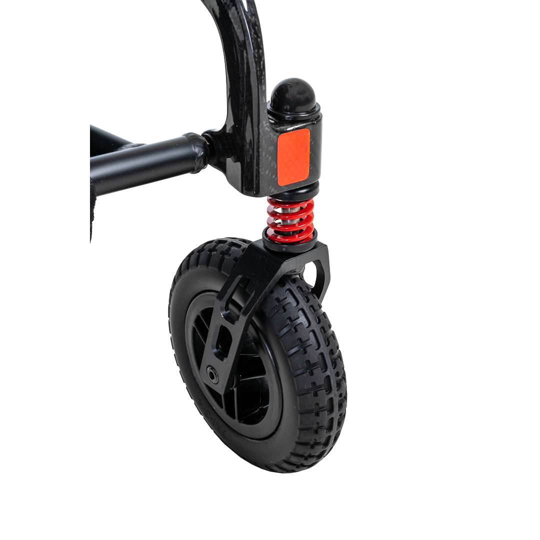 Close-up of a black and red sturdy wheel with textured tire and suspension spring on the metal frame of the Pride Mobility Jazzy® Carbon Ultralite Powerchair. This ultra-lightweight design provides maneuverability and stability, perfect for individuals on the go.