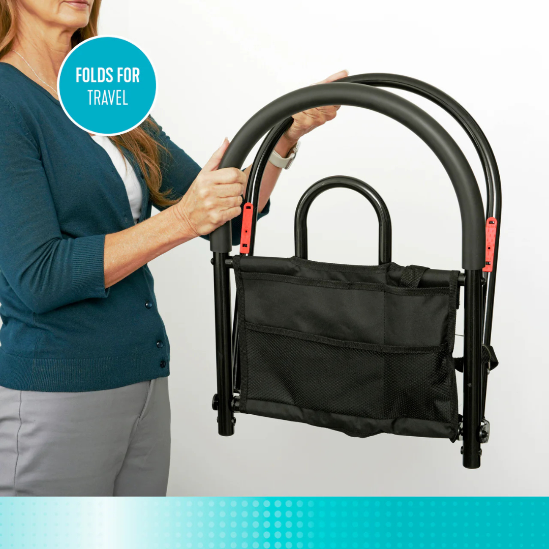 A woman in a teal cardigan holds the Stander Bed Rail Advantage Traveler—a black, foldable bed safety rail with a carry pouch. A circular label reads "FOLDS FOR TRAVEL." The white background features a blue gradient, evoking portable and bariatric support designs.
