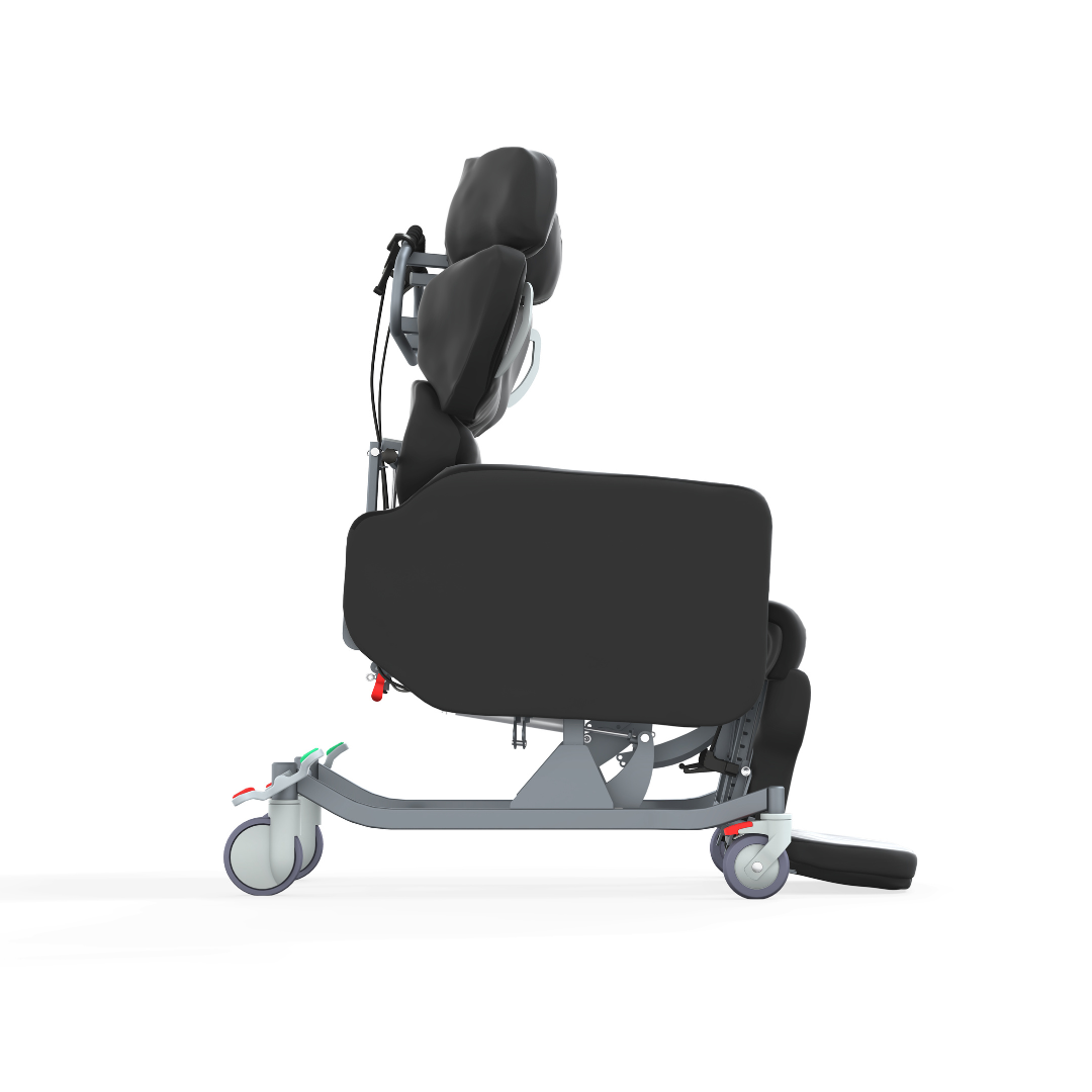 Side view of the Accora Configura® Advance Postural Tilt Chair in black with padded head, back, and leg support. The ergonomic chair has a metal frame, wheels, footrests, adjustment levers, and a modern design for advanced postural care.