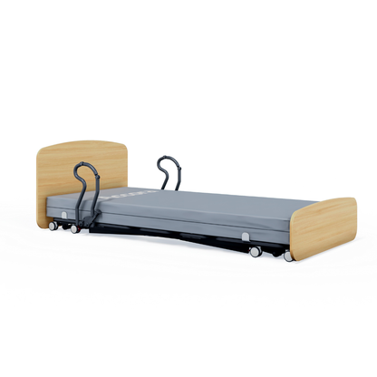 The Accora Contesa® FloorBed® Hi/Low Full Electric Bed has a gray mattress, wooden head/footboards, safety rails, and wheels for mobility. Its low height helps prevent falls by keeping the bed close to the floor.