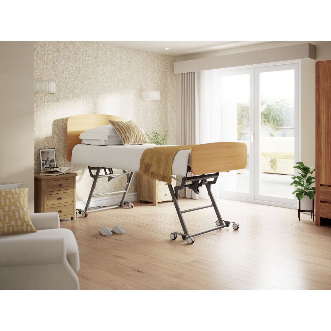 A modern bedroom with an Accora Contesa® FloorBed® Hi/Low Full Electric Bed—adjustable for fall prevention—adorned with a yellow blanket and pillow, plus a bedside table, armchair, lush plants, and large windows with sheer curtains.