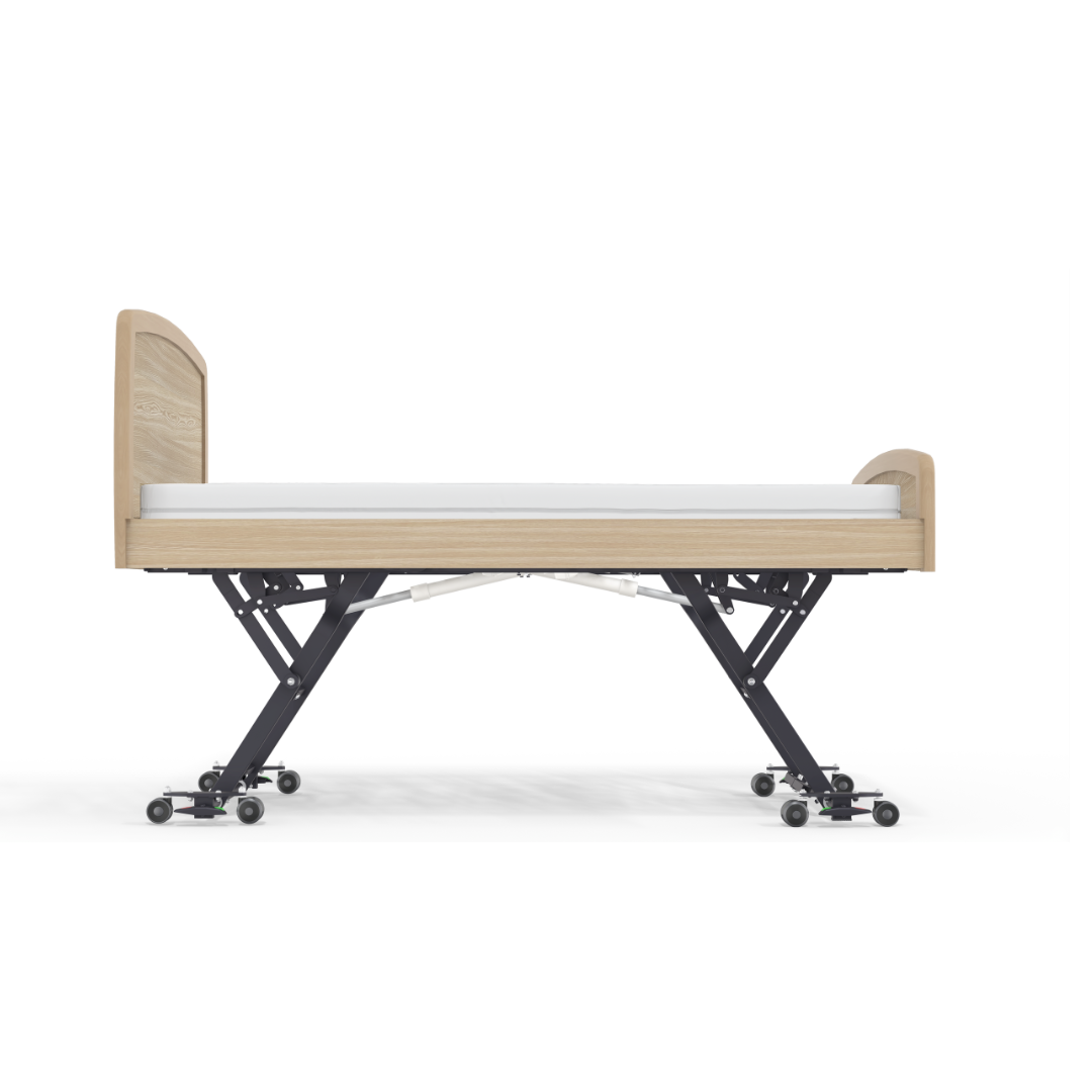 The Accora Empresa® Full Electric Bariatric FloorBed® is shown from the side, featuring a modern design with a light wood frame, white mattress, and black metal legs on wheels—ideal for healthcare settings needing style and function.