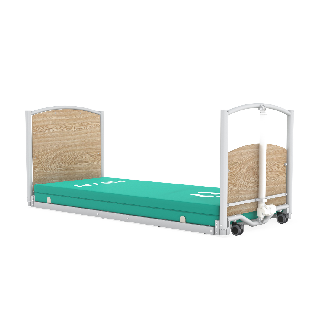 The Accora FloorBed® Ultra Low Full Electric Homecare Bed features wooden head and foot panels, a green Accora-labeled mattress, and a white metal frame, sitting ultra low for enhanced safety and accessibility.