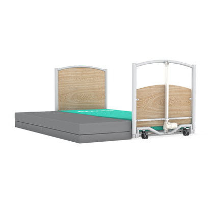 The Accora FloorBed® Ultra Low Full Electric Homecare Bed features a light wood headboard and footboard, a green surface area with grey mattress sections, is low to the ground, and has wheels visible on the footboard.