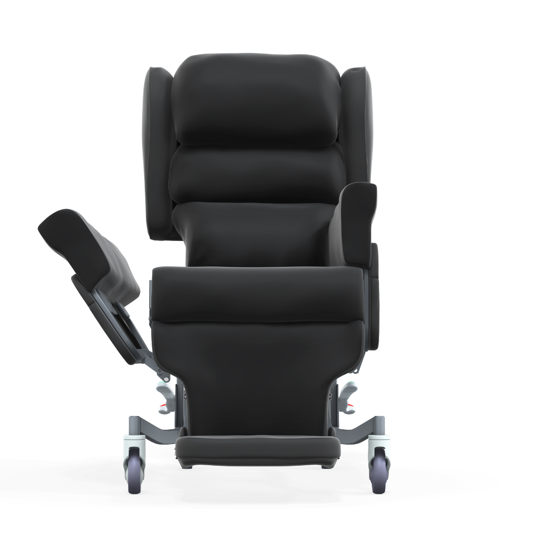 Front view of the Accora Configura® Advance Postural Tilt Chair, a black reclining chair with padded seat, armrests, extended leg rest, and four wheels, shown isolated on a white background.
