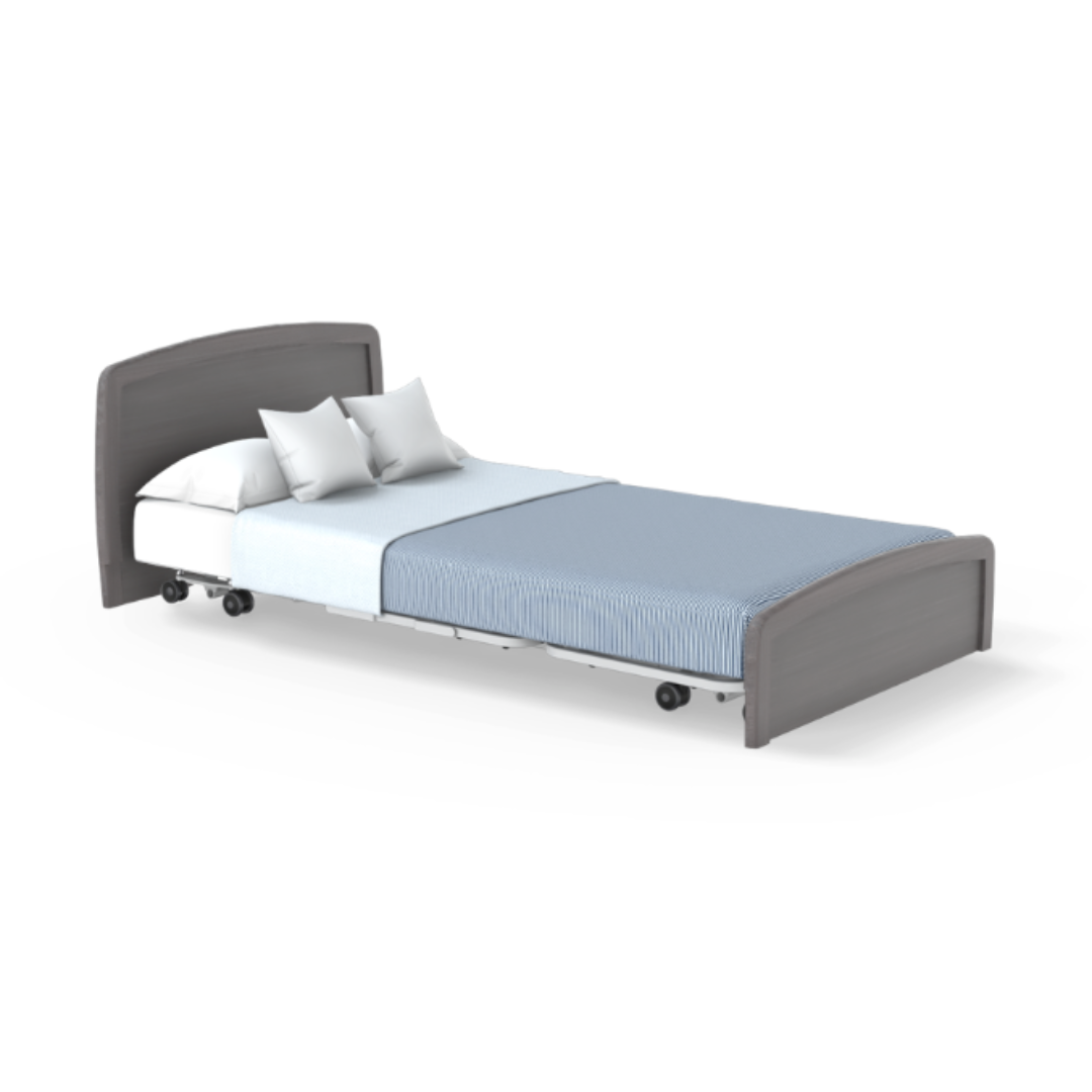 The Accora Empresa® Full Electric Bariatric FloorBed® features a gray wooden frame, white mattress, two white pillows, a light blue blanket, and wheels for mobility. Shown against a clean white background for versatile styling.