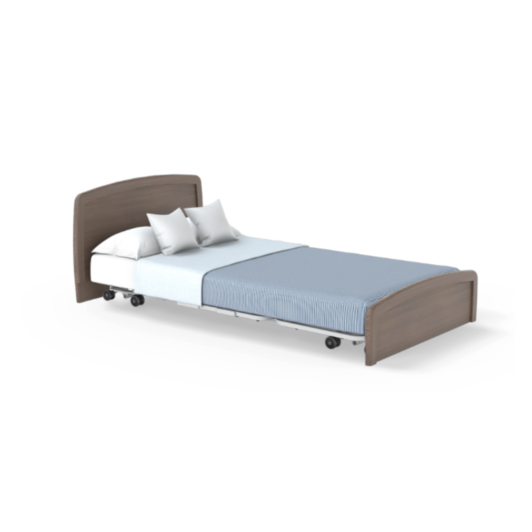 The Accora Empresa® Full Electric Bariatric FloorBed® is shown with a wooden headboard and footboard, white sheets, blue striped blanket, two pillows, and wheels for mobility—all isolated on a white background.