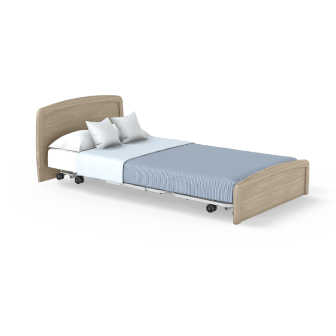 The Accora Empresa® Full Electric Bariatric FloorBed® is shown with a light wood headboard and footboard, white sheets, blue blanket, two white pillows, and four wheels for mobility against a plain white background.