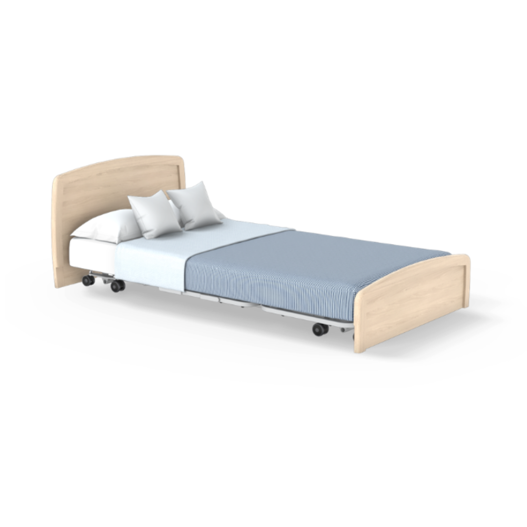 The Accora Empresa® Full Electric Bariatric FloorBed® features a light wood headboard and footboard, blue and white bedding, two white pillows, and wheels on the frame, shown isolated on a white background.
