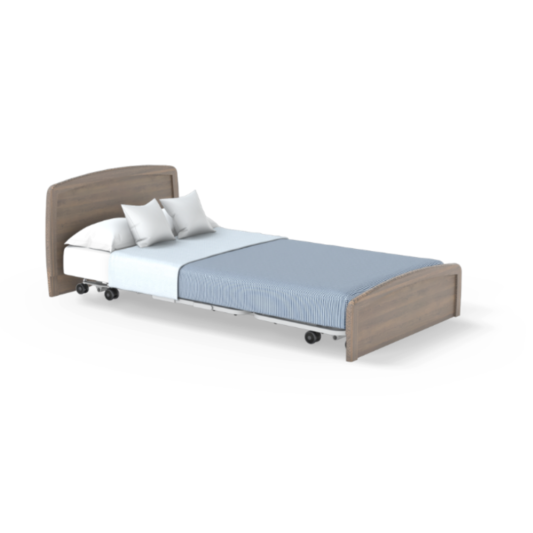 The Accora Empresa® Full Electric Bariatric FloorBed® features a light wood headboard and footboard, sturdy white mattress, two pillows, light blue blanket, and wheels; displayed against a plain white background.