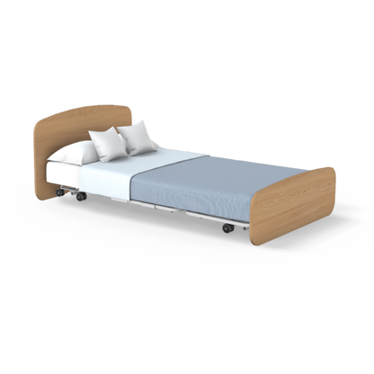 The Accora Empresa® Full Electric Bariatric FloorBed® is a single hospital bed with light wood headboard and footboard, white frame, blue blanket, white sheet, two white pillows, and wheels for easy mobility.