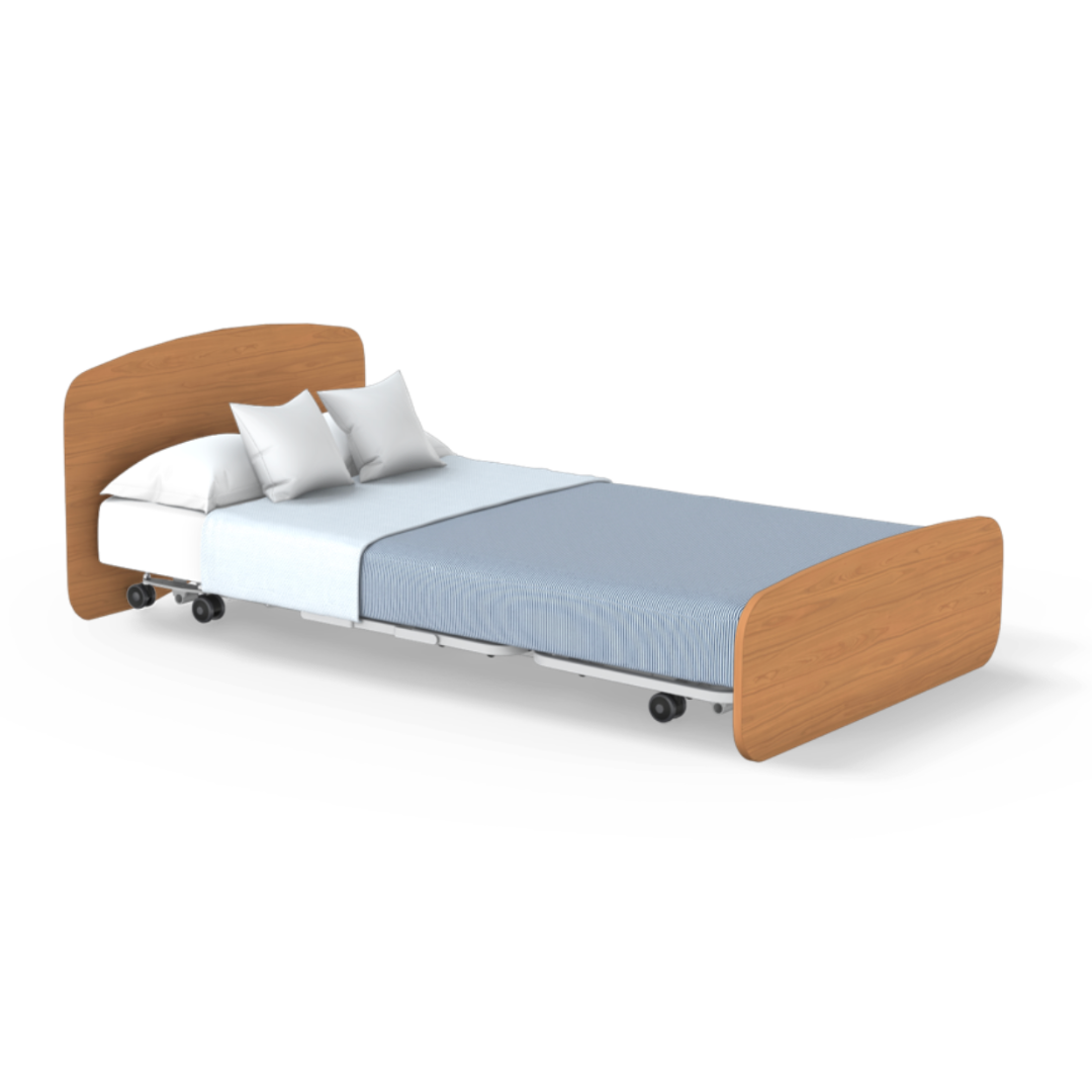 The Accora Empresa® Full Electric Bariatric FloorBed® features a light wood headboard and footboard, sturdy metal frame, wheels, white pillows and sheet, plus a light blue blanket—ideal for modern care facility layouts.