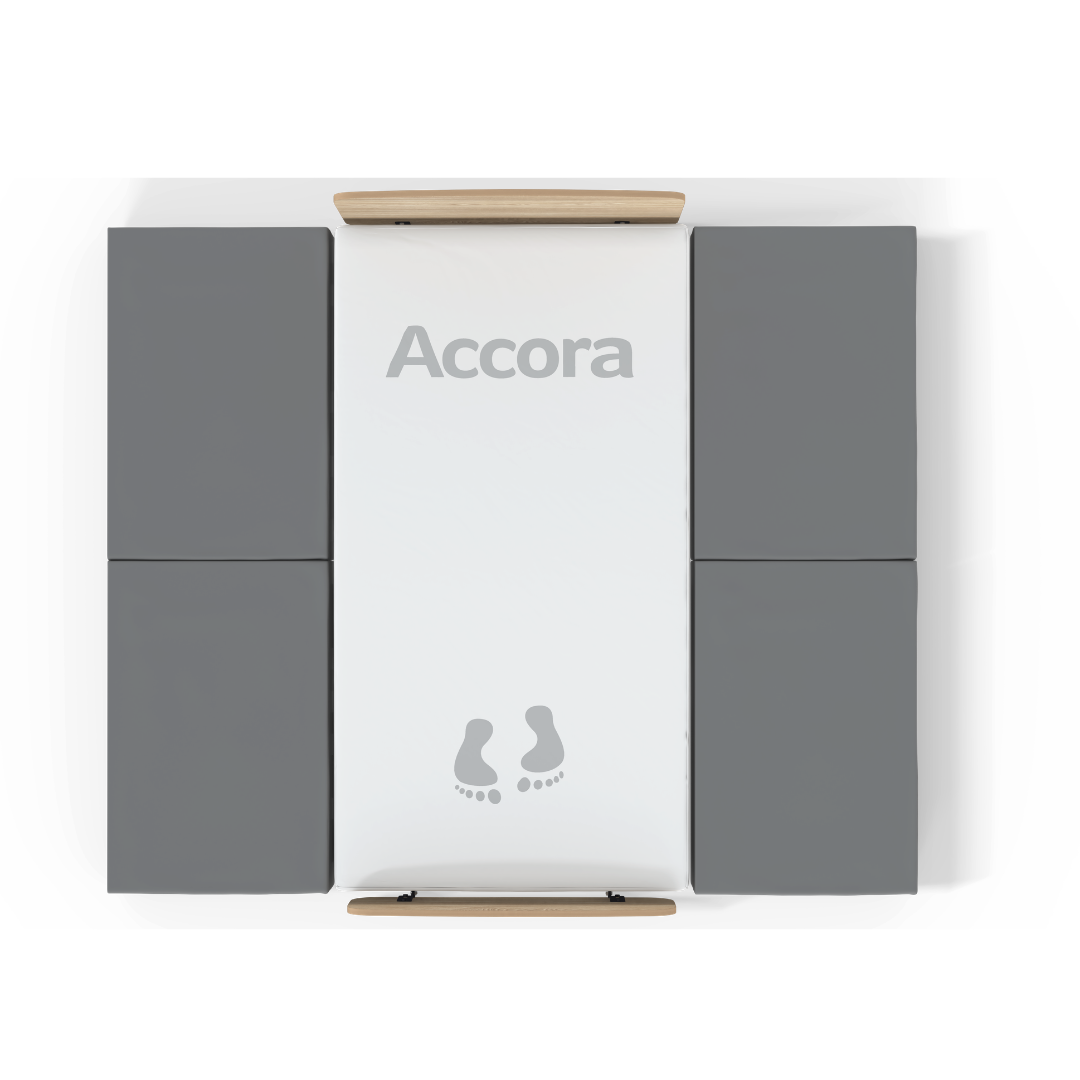 Overhead view of the High Safety Mat For Bedside Falls: a white rectangular Accora platform with gray padding on both sides, wooden bars at each end, and illustrated footprints near the bottom for high-impact fall protection.