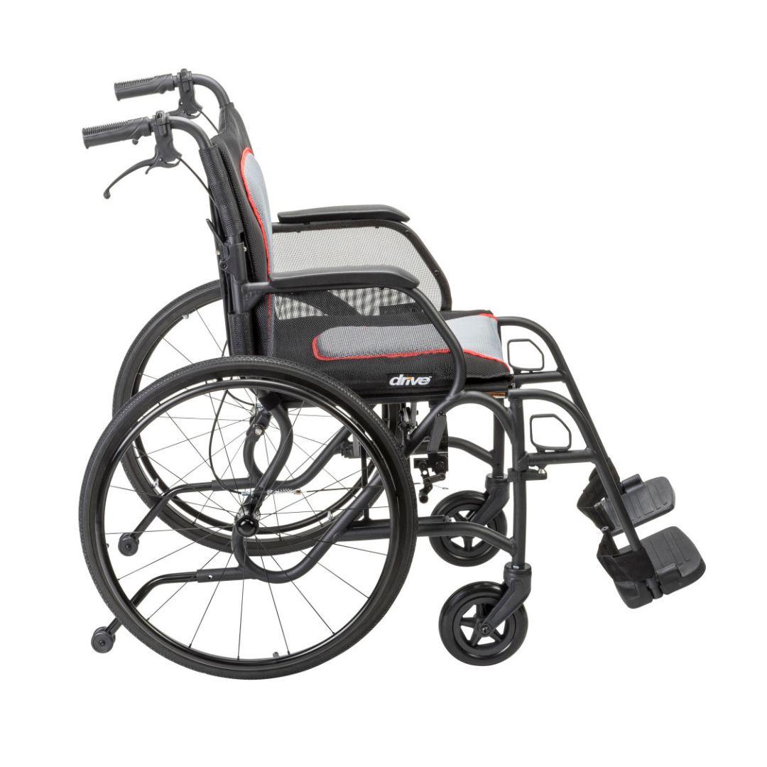The Drive AeroFly™ Ultra-Lite Wheelchair with Companion Brakes is a lightweight, black travel wheelchair featuring large rear wheels, small front wheels, footrests, a mesh backrest, and the Drive brand on its frame.